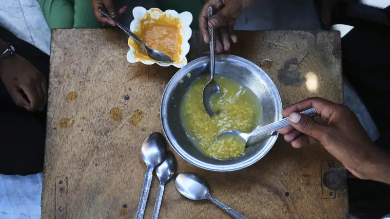 আল-আরজা পরিবার তাবুর ভেতরে লাল ডালের পাতলা স্যুপ খাচ্ছেন, যা তারা অনেক পানি মিশিয়ে রান্না করেছেন যেন বেশি দিন চলে। স্থান: মুওয়াসি, খান ইউনুস, গাজা; তারিখ: ২১ মে ২০২৫। (ছবি: আবদেল কারিম হানা, এপি)