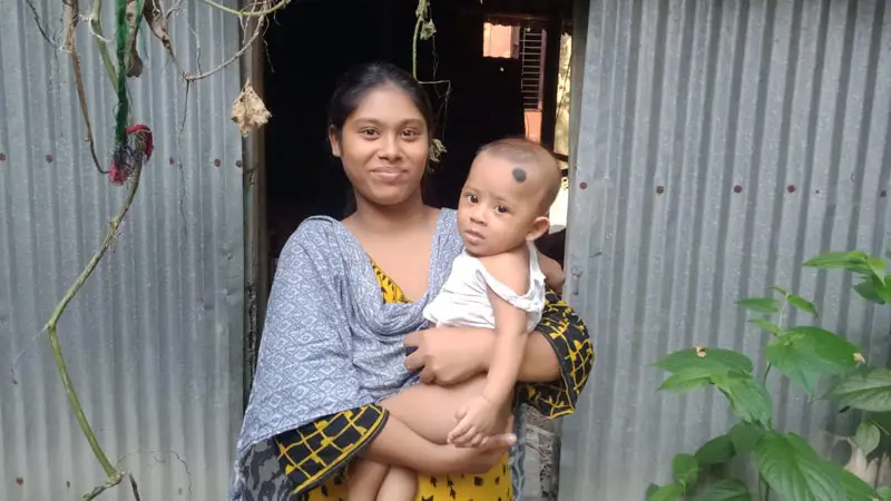 সন্তান কোলে নিয়ে নিজের ভাঙাচোরা ঘরের সামনে সাথী আক্তার। ছবি: জনকণ্ঠ
